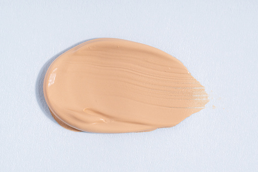 A smear of foundation cream or concealer on a white background, macro. Texture of cosmetic liquid foundation or beige cream smudge, smear, stroke. Advertising of professional cosmetics.