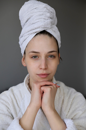Portrait of a beautiful girl at home with a towel on her head in a bathrobe.