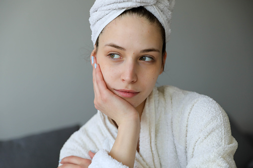 Portrait of a beautiful girl at home with a towel on her head in a bathrobe.