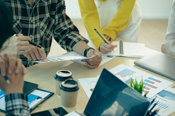 istock Group of confident businessmen pointing at laptops, graphs and charts to analyze market data, account balance sheet, net profit to plan new sales strategy. Close-up pictures 1692120202