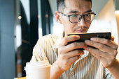 Close-up Asian man with eyeglasses using phone