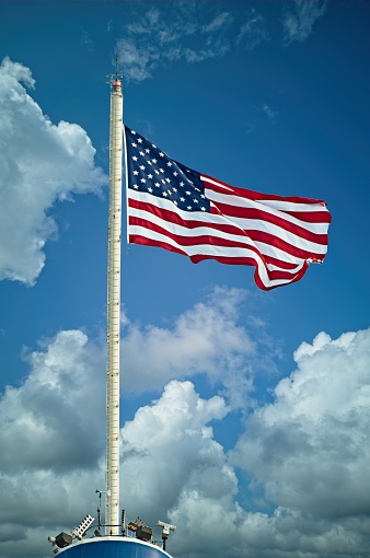 A 15 star American flag flying on a pole on a windy day.