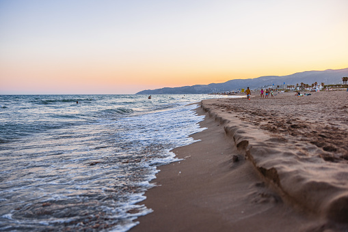 Amazing sunset sky over the beautiful Barceloneta beach in the summer. The sky is colorful. The beach is sandy.