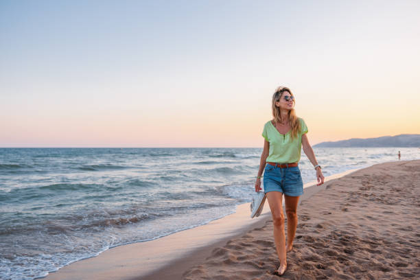 istock Relaxed Young Caucasian Woman Enjoying Her Walk On A Sandy Beach While The Sun Is Setting 1692136143
