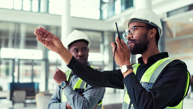 People, teamwork and engineer talking on a walkie talkie for project management and planning. Construction, maintenance and inspection with black men or staff at office building with communication