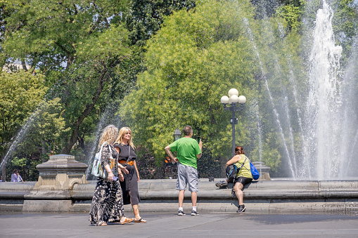 Washington Square Park, Manhattan, New York, USA - August 9th 2023:  Tourists taking pictures of each other in front of the fountain in the famous park