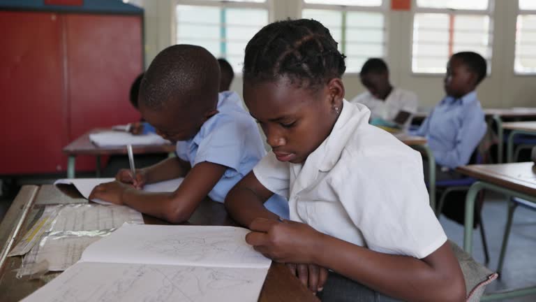 Close-up. Black African school children drawing at a desk in a classroom in Africa