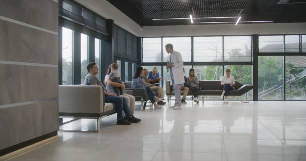 doctor speaks with elderly couple in clinic lobby area - airport waiting room waiting airport lounge imagens e fotografias de stock