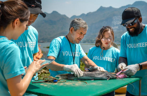 istock group of volunteers working by the river, african man pulling trash out of dead fish 1692153476