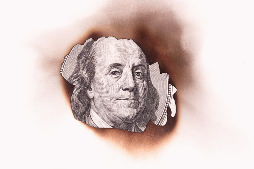 burning dollar bill as a symbol of inflation and the financial crisis