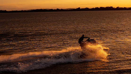 A man riding a jetski at sunset on the Orla do Guaiba river in Brazil