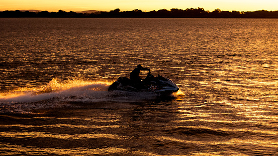 A man riding a jetski at sunset on the Orla do Guaiba river in Brazil