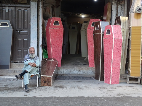 Peshawar, Pakistan. Coffin makers await customers in the backstreets of Peshawar. Coffins made from wood with a formica covering, and not forgetting a small window for a view. Peshawar, Pakistan. Photo taken 04/14/2023