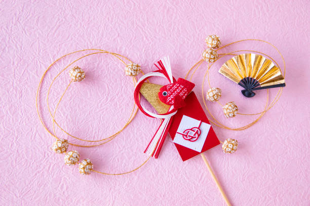 ピンクの背景に金色の扇と赤い鯛の装飾とテマリ。日本のお正月の画像。