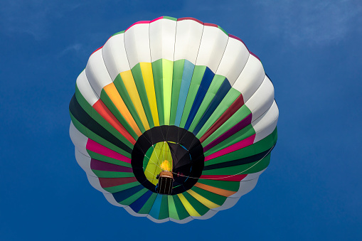 The view of a hot air balloon from underneath with the flame visible heating up the balloon.