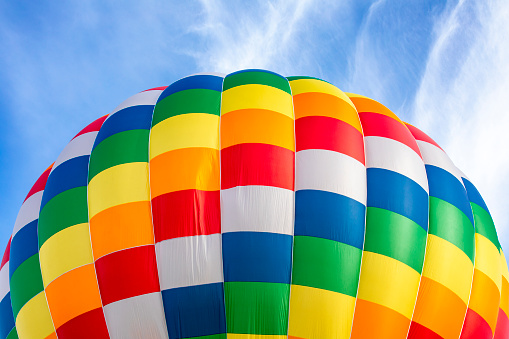 Yellow, red and blue hot air balloon flying overhead in a clear blue sky.