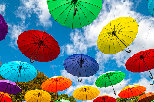 Many colorful umbrellas as decoration in a city street against blue sky