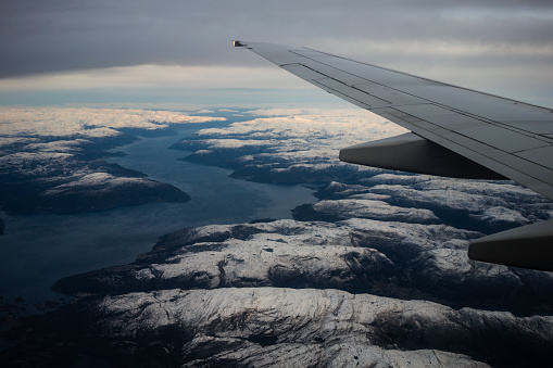 Passenger view from an airplane over the fjords of Norway, with snow over the mountains