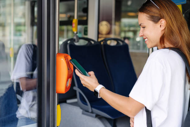 istock Attractive young woman paying shuttle bus using her mobile phone, contactless technology of payment in public transport. 1692216361