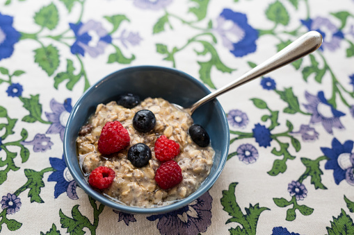 A bowl of gluten free and dairy free oats with raspberries and blue berries homemade for a healthy breakfast or snack