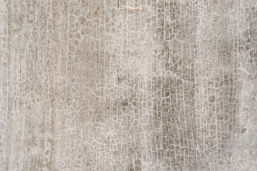 The surface of a raw concrete wall features a grainy, harsh, raw, uneven, and porous texture.