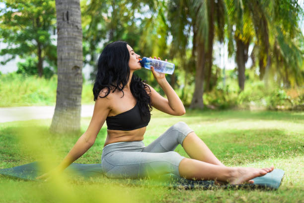 ukrainische schöne frau, die wasser trinkt, nachdem sie draußen yoga auf der karte gemacht hat - exercising sensuality water bottle relaxation exercise stock-fotos und bilder