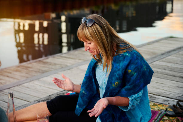 istock Woman sitting on blanket at waterfront 1692234955