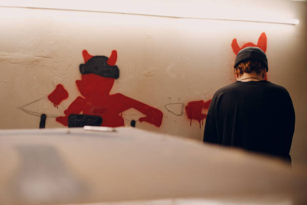保護マスクにペンキを手にしたスプレー風船を持つ若い女性が、壁のガレージのストリートアートの落書きを描く - graffiti men wall street art ストックフォトと画像