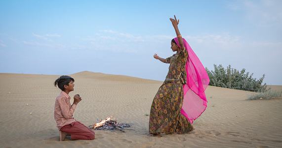 Happy Indian girl dancing on a sand dune, desert village, India