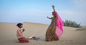 Happy Indian girl dancing on a sand dune, desert village, India