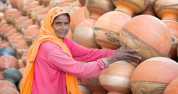 Indian woman arranges clay pots in The Pink City of Jaipur, Rajasthan, India. Jaipur is known as the Pink City, because of the color of the stone exclusively used for the construction of all the structures.