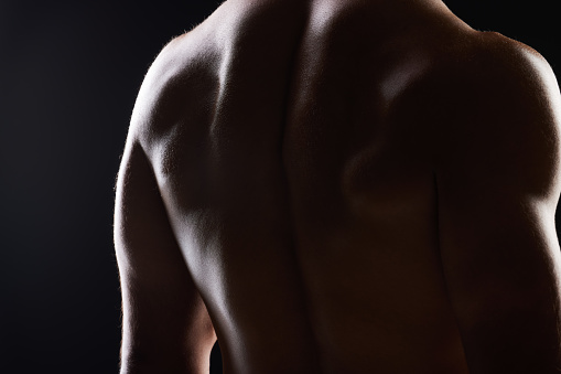 Strong back, dark studio and person with ripped body, fitness transformation goals and muscle building results. Bodybuilder training exercise, shadow light and muscular athlete on black background