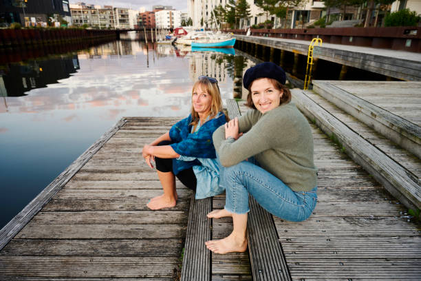 Two adult women having a nice time at the waterfront a beautiful evening with water reflecting the sky