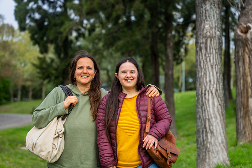 Front view of mother and daughter with down syndrome taking a walk at park