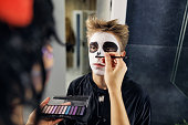 Mother painting teenage son's face for Halloween