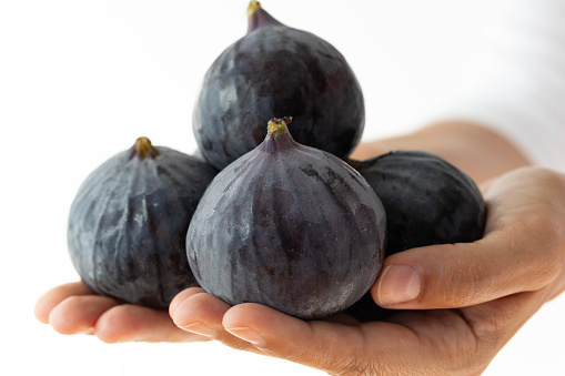 Woman holding figs, white background.