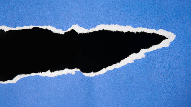 istock Torn blue paper sheet isolated on black background 1692317166
