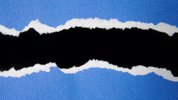 istock Torn blue paper sheet isolated on black background 1692317860