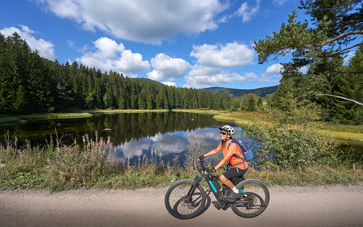 nice senior woman on her electric mountain bike cycling at Lake Schluchsee in the German Black Forest near Titisee-Neustadt, Baden-Württemberg, Germany
