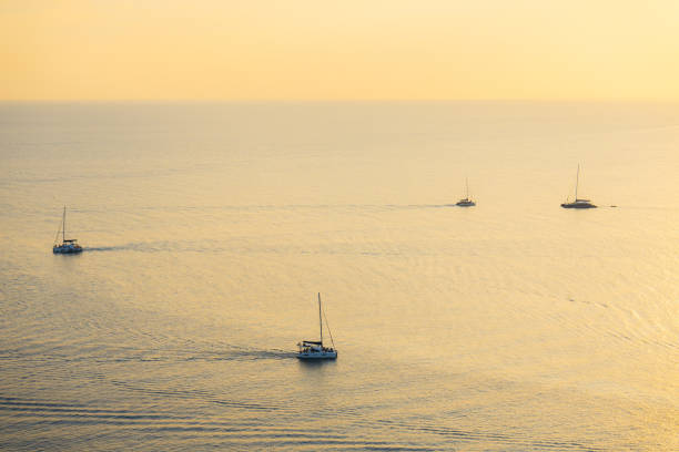 Scenic view of distant yachts at sea at sunset