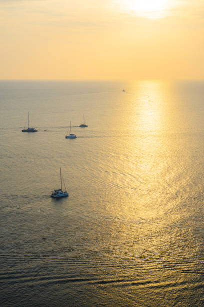 Scenic view of distant yachts at sea at sunset