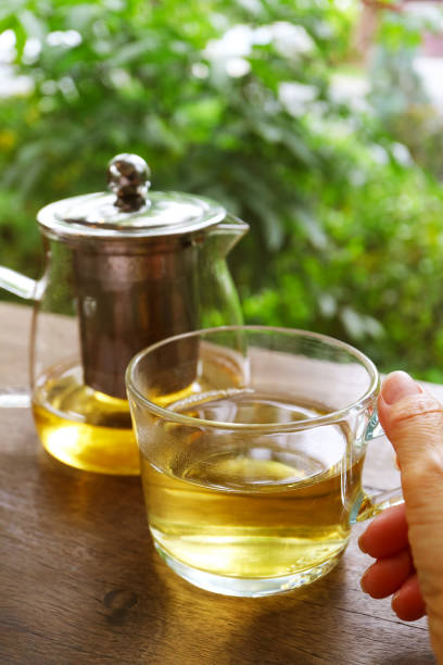 istock Hand holding a cup of hot tea with blurry tea pot in the backdrop 1692334275