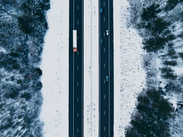 autopista a través de un paisaje de bosque nevado visto desde arriba - highway traffic aerial view netherlands fotografías e imágenes de stock