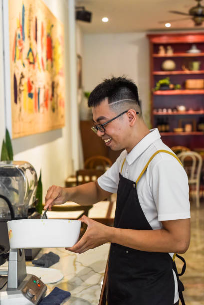 istock Vietnamese man chef in uniform holding spoon and bowl with liquid dough for belgian waffles 1692355043