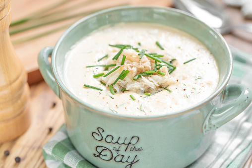 Homemade creamy crab soup served in a green bowl. A rich and creamy soup made of heavy cream,  vegetables, crabmeat and seasonings in a Carolina-style she-crab soup