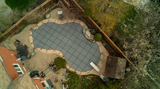 An aerial view of a safety cover over a swimming pool in the backyard on a spring day