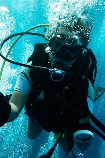 A man and a woman couple doing scuba diving near a shipwreck