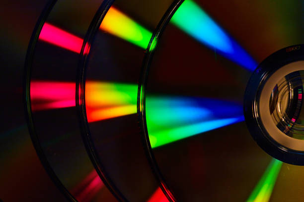 istock Abstract stack of four dark silvery CDs with reflective rainbow colored bursts of light on surface 1692367812