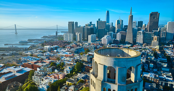 Image of Aerial of roof of Coit Tower overlooking downtown skyscrapers and Oakland Bay Bridge