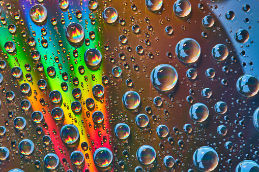 Colorful window glass with raindrops and water drippings
